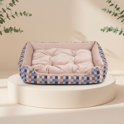 Cama para mascotas DELONEA SnoozePup con interior acolchado beige y exterior de tela a cuadros azules y marrones.